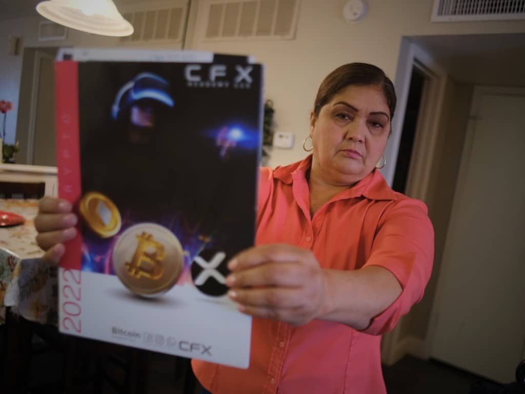 Reina Ochoa, de Honduras, sostiene un folleto de la empresa CryptoFX