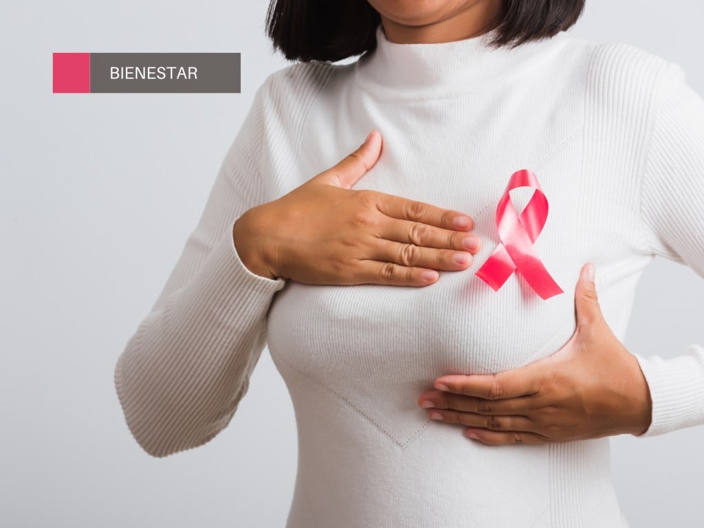 Mujer realizando un autoexamen mamario y lazo rosa de prevención contra el cáncer de mama