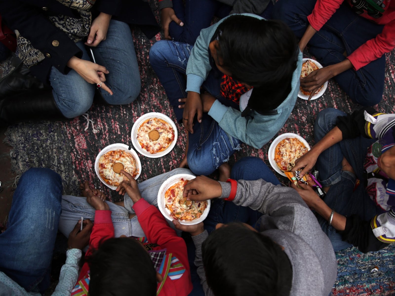Niños comiendo pizza. Foto: Raminder Pal Singh, EFE/EPA