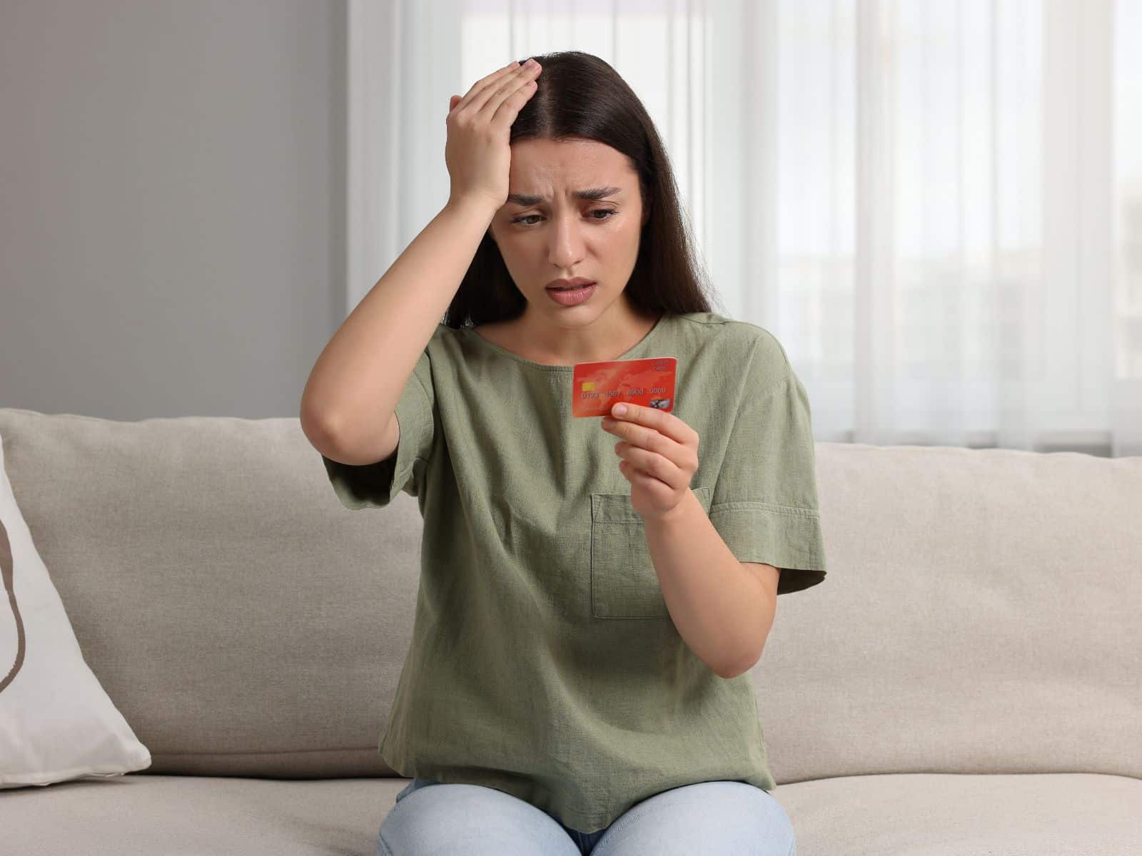 Fotografía de una mujer preocupada que sostiene una tarjeta bancaria