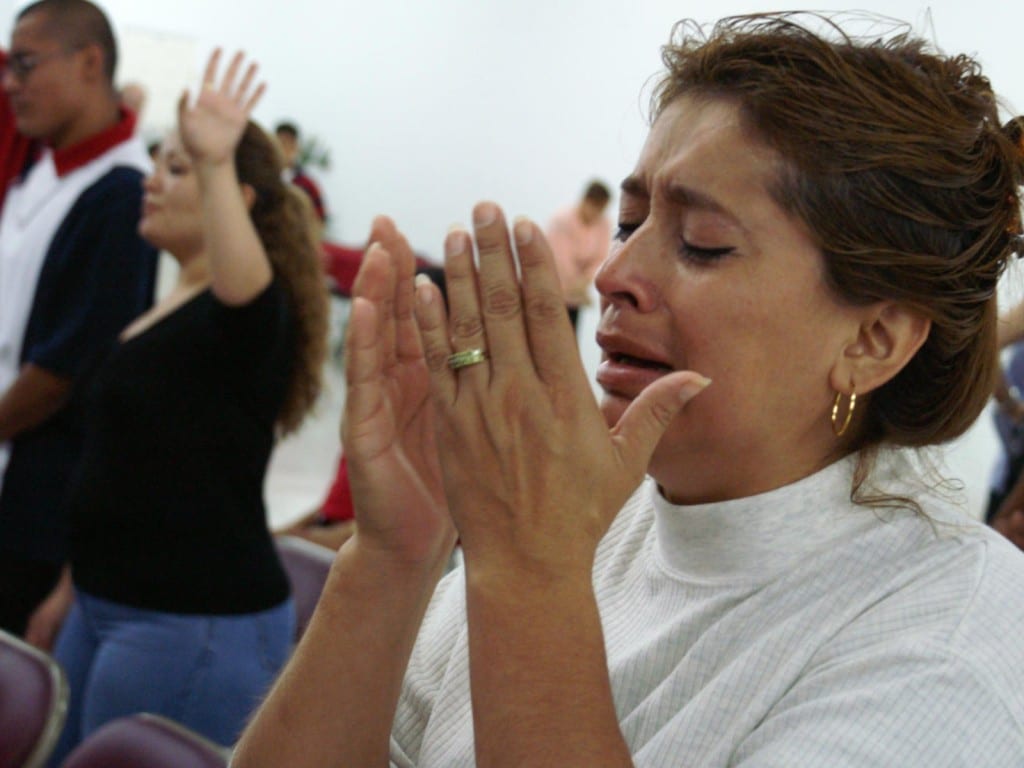 Una mujer hispana no identificada reacciona durante un servicio religioso