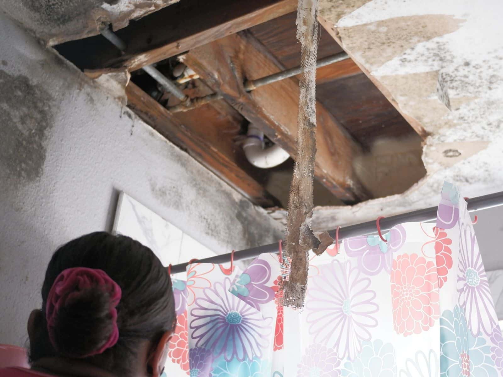 Inquilina en el baño de su apartamento cuyo techo ha colapsado